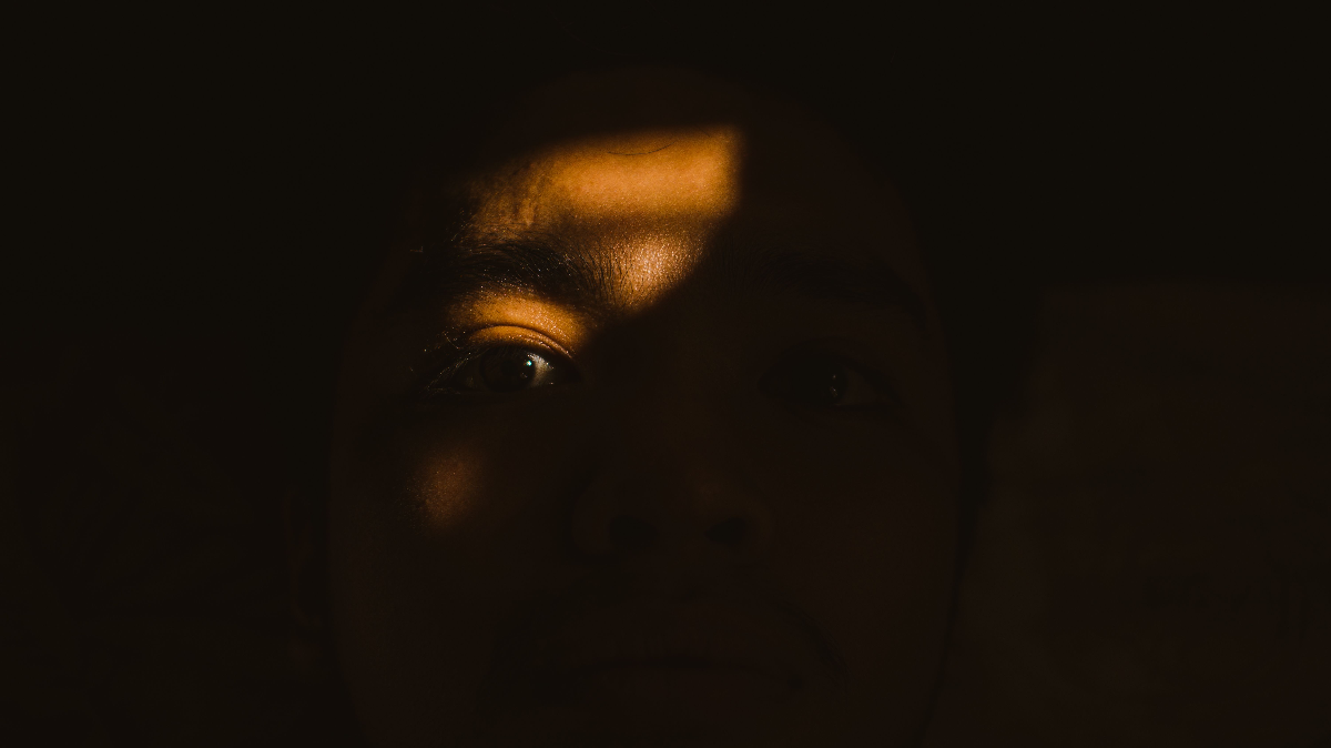 A close portrait lit by warm bands of light